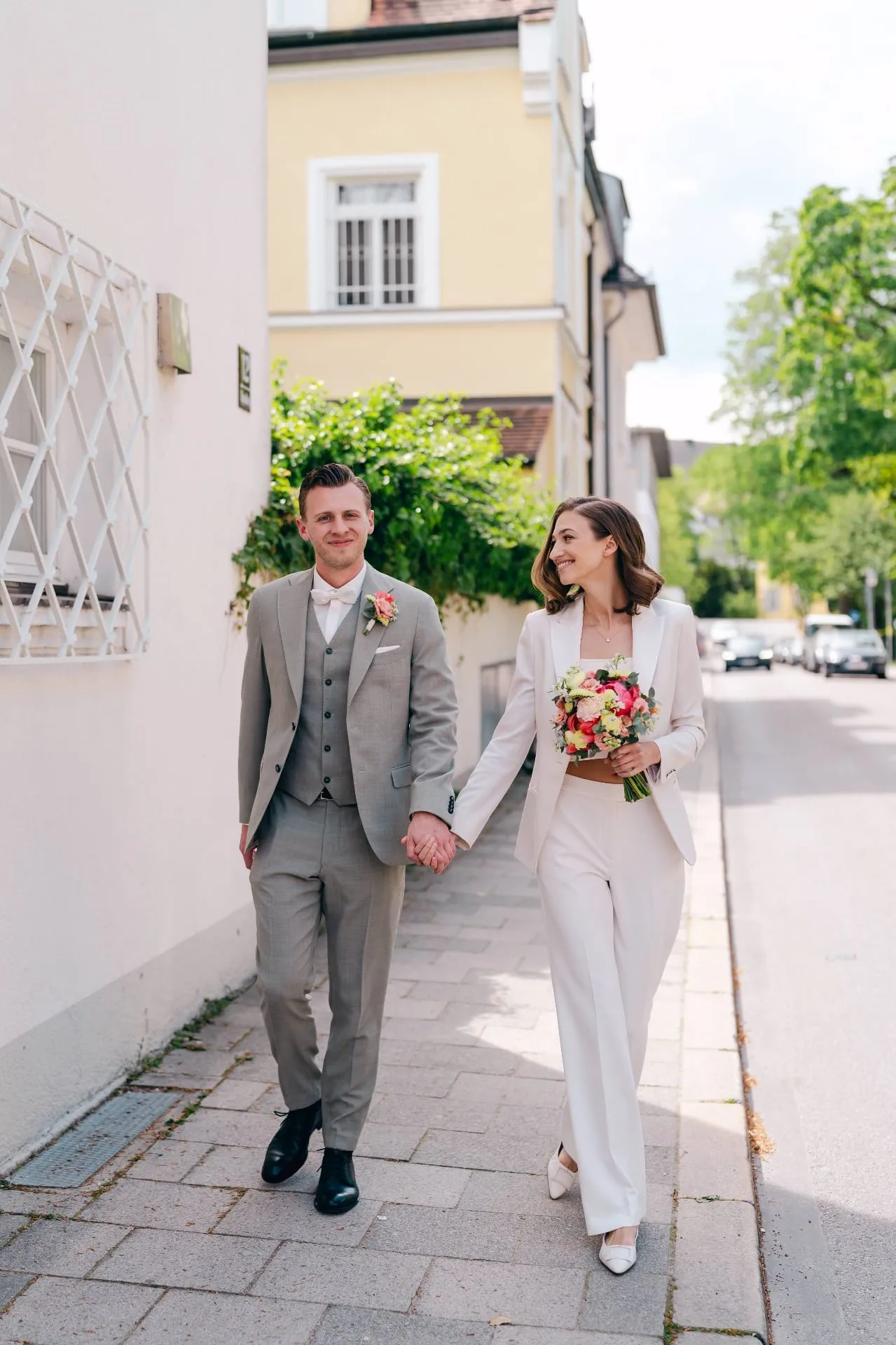 Brautpaar beim Spaziergang durch die Münchner Straßen, authentische Hochzeitsfotografie Schwabing